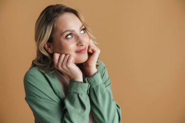 Mutlu güzel bir kadın gülümsüyor ve bej duvarın üzerinden yukarıya bakıyor.