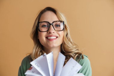 Çekici, mutlu, gözlüklü, gri arka planda izole edilmiş ders kitaplarını tutan genç bir kadın portresi. Eğitim fakültesi konsepti. Pozitif duygular, yüz ifadesi