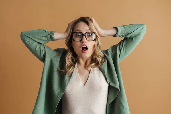 Geschokt Mooie Vrouw Bril Grijpen Haar Hoofd Geïsoleerd Beige Muur — Stockfoto