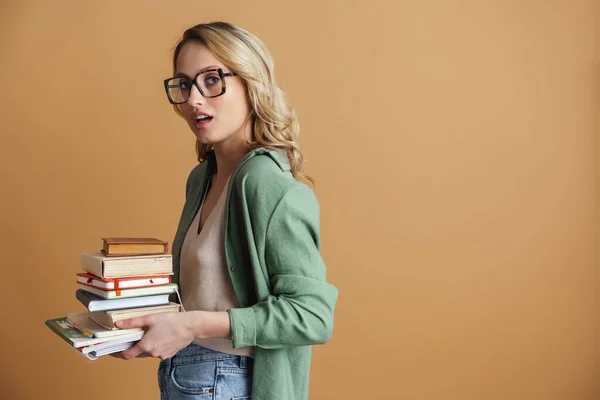 漂亮超载的女孩戴着眼镜站在与书隔离灰色背景 — 图库照片
