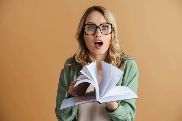 Aşırı Yüklenmiş Gözlüklü Bir Kız Gri Arka Planda Kitaplarla Ayakta — Stok fotoğraf