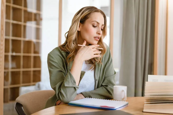 Mujer Rubia Blanca Joven Pensativa Escribiendo Notas Mientras Está Sentada — Foto de Stock