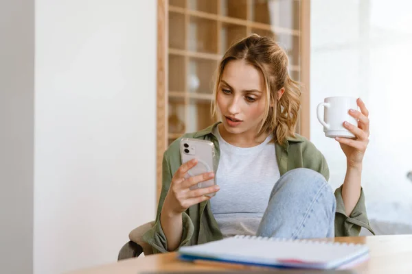 Fiatal Fehér Használ Okostelefon Miközben Iszik Kávét Otthon — Stock Fotó