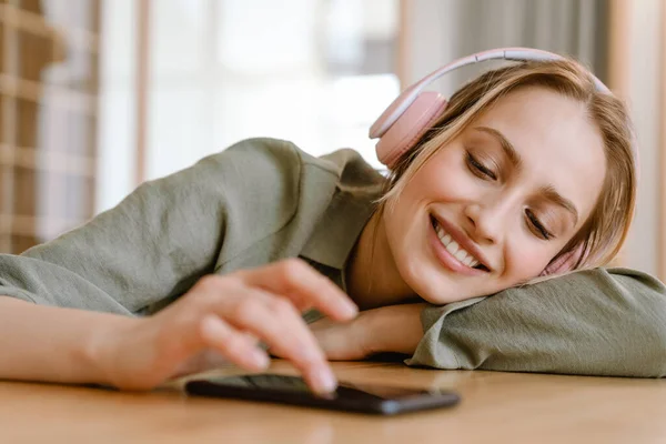 Νεαρή Γυναίκα Χαμογελά Ακούγοντας Μουσική Κινητό Και Ακουστικά Στο Σπίτι — Φωτογραφία Αρχείου