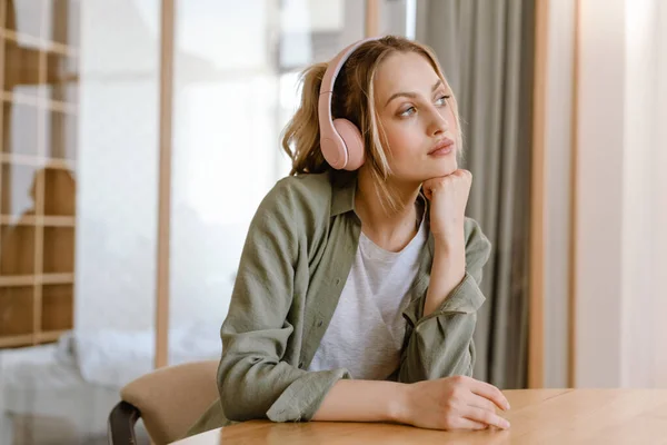 Glimlachende Jonge Blonde Blanke Vrouw Koptelefoon Zitten Aan Muur Thuis — Stockfoto