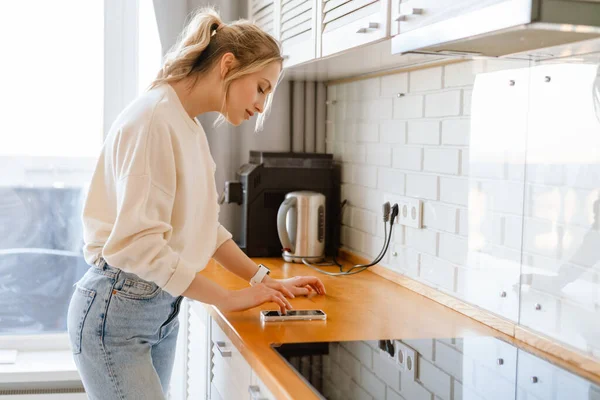 Jovem Mulher Usando Telefone Celular Enquanto Está Cozinha Casa — Fotografia de Stock