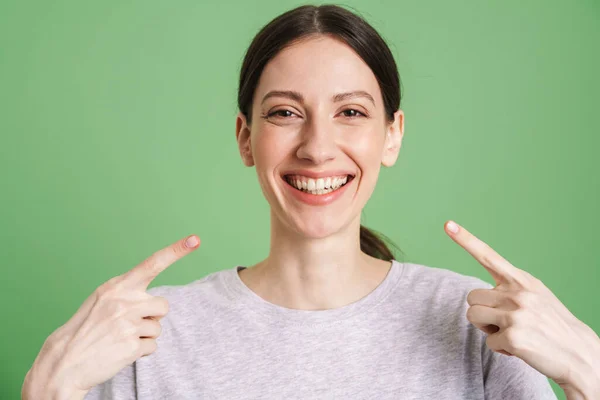 笑着的年轻女子露出完美而直白的牙齿 站在绿色的背景上 — 图库照片