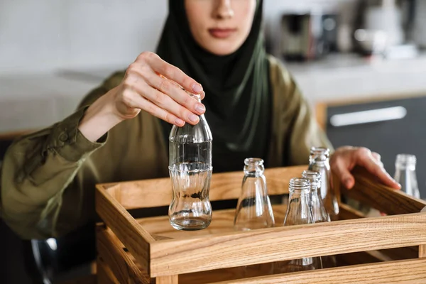 年轻的穆斯林妇女坐在厨房的桌子旁 头戴头巾 对废物进行分离 — 图库照片