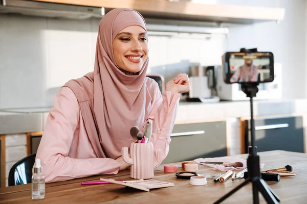穆斯林妇女在家里展示美容产品的同时 还在手机上自拍了一段视频 — 图库照片