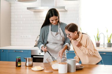 Mutfakta krep hamuru yaparken gülümseyen güzel anne ve kız.