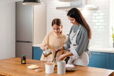 Mutfakta krep hamuru yaparken gülümseyen güzel anne ve kız.