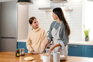 Mutfakta krep hamuru yaparken gülümseyen güzel anne ve kız.