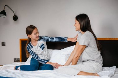 Güzel bir anne ve kız evdeki yatakta otururken konuşuyorlar.