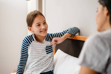 Güzel bir anne ve kız evdeki yatakta otururken konuşuyorlar.