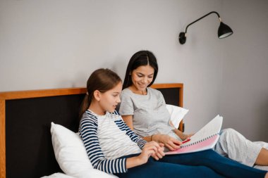 Mutlu anne ve kız evde yatarken ödev yapıyor.