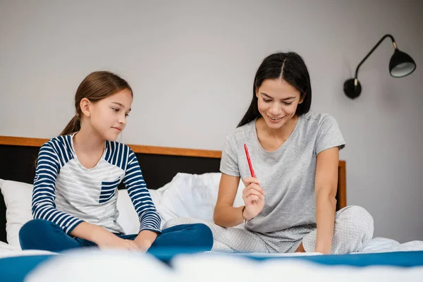 Güzel Bir Anne Kız Evde Yatakta Otururken Ödev Yapıyor — Stok fotoğraf