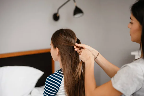 Bonita Hermosa Madre Haciendo Peinado Hija Mientras Está Sentada Cama — Foto de Stock