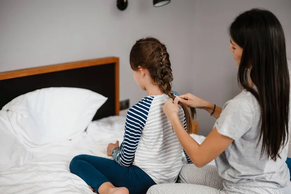 Mãe Bonita Agradável Fazendo Penteado Para Sua Filha Enquanto Sentada — Fotografia de Stock