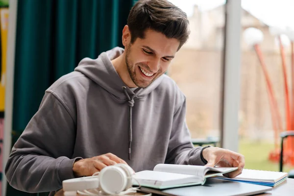 Glimlachende Jongeman Boek Lezen Tijdens Het Studeren Cafe Binnen — Stockfoto