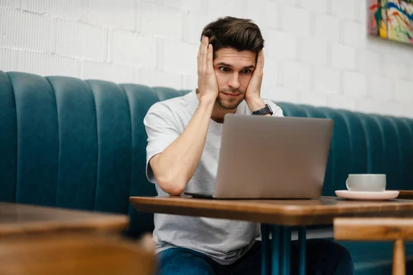 Estudiante Joven Confundido Sentado Cafetería Interior Con Computadora Portátil Estudiando — Foto de Stock