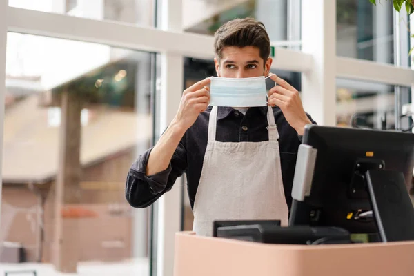 Young Man Apron Wearing Protective Medical Mask Standing Cash Register — Stock Photo, Image