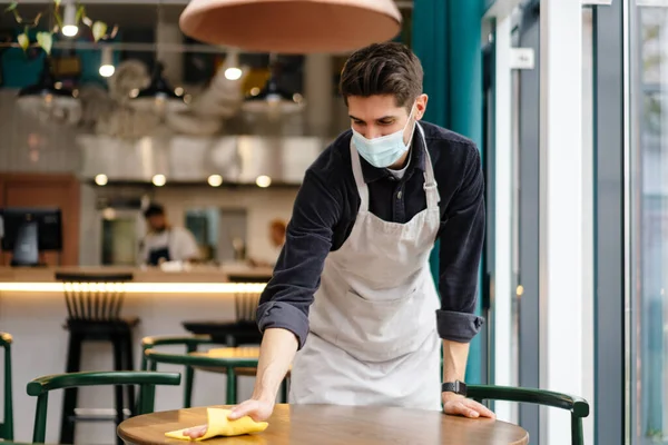 Homme Serveur Portant Masque Désinfectant Table Dans Café Intérieur — Photo
