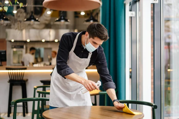Homme Serveur Portant Masque Désinfectant Table Dans Café Intérieur — Photo