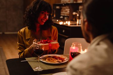 Beyaz adam lokantadaki randevusunda kız arkadaşına hediye veriyor.