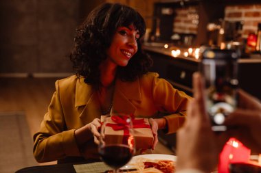 Beyaz adam evde romantik bir akşam yemeği sırasında kız arkadaşının fotoğrafını çekiyor.