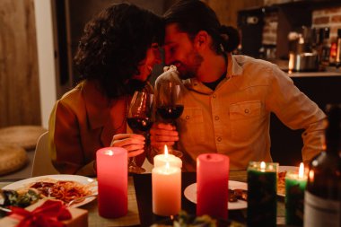 Beyaz çift evde romantik bir akşam yemeği yerken sarılıyor.