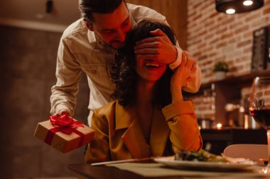 Beyaz adam evde romantik bir akşam yemeği sırasında kız arkadaşına hediye veriyor.