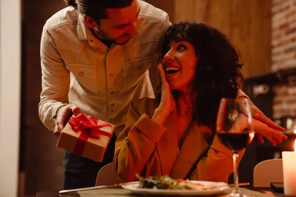 Beyaz adam evde romantik bir akşam yemeği sırasında kız arkadaşına hediye veriyor.