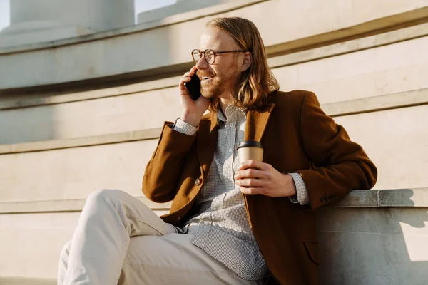 Hombre Jengibre Hablando Teléfono Móvil Beber Café Mientras Está Sentado — Foto de Stock