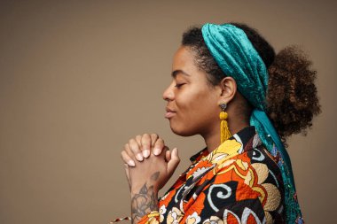 Gri arka planda izole edilmiş, profilde poz verirken el ele tutuşan genç siyahi kadın.