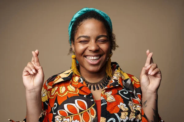 Saçbandı takmış, gülen ve el kol hareketi yapan genç siyahi bir kadın gri arka planda izole edilmiş.