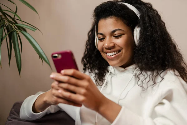 Young Black Woman Headphones Using Cellphone While Sitting Sofa Home — Stock Photo, Image
