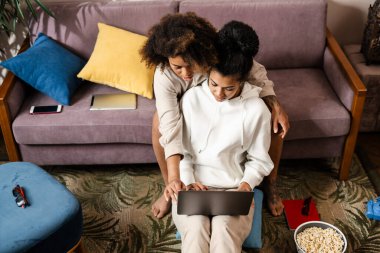 İki Afrikalı genç kadın dizüstü bilgisayarlarıyla bir kanepede oturup ekran görüntüsüne bakıyorlar.