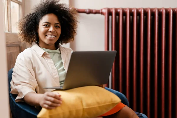 Genç Siyahi Kadın Evdeki Koltukta Otururken Dizüstü Bilgisayar Kullanıyor — Stok fotoğraf
