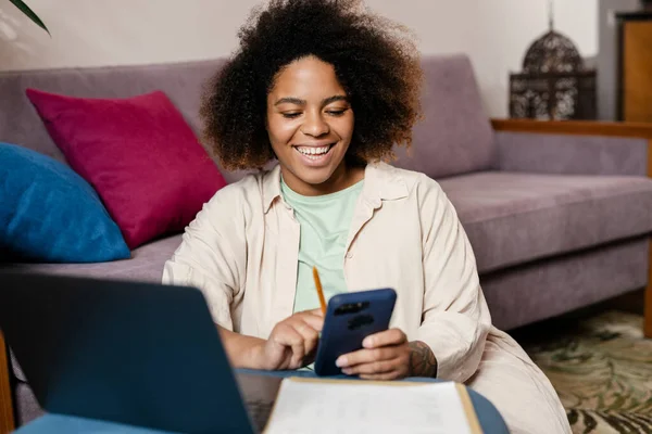 Ung Svart Kvinna Som Använder Mobiltelefon När Arbetar Med Bärbar — Stockfoto