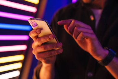 Beyaz adam gömleğini giymiş, cep telefonuyla içeride yazı yazıyor.