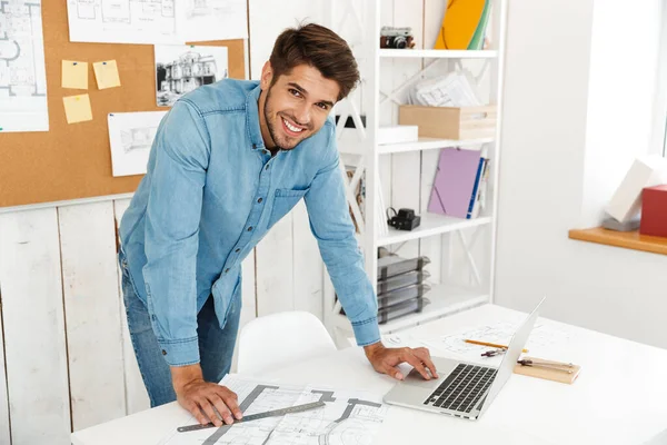 Jovem Homem Branco Sorrindo Enquanto Trabalhava Com Laptop Desenhos Escritório — Fotografia de Stock