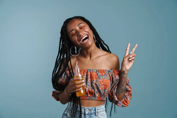 Młoda Czarna Kobieta Pije Napój Pokazując Gest Spokoju Odizolowany Niebieskim — Zdjęcie stockowe