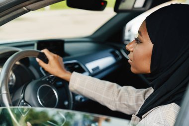Siyah Müslüman kadın araba kullanırken başörtüsü takıyor.