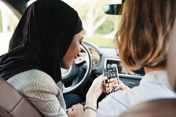 Дві Багаторасові Жінки Використовують Мобільний Телефон Сидячи Машині — стокове фото