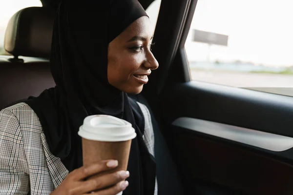 穿着头巾的黑人穆斯林妇女在开车时喝咖啡 — 图库照片