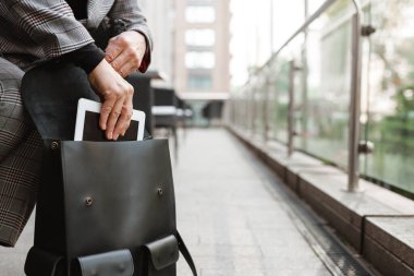 Dışarıdaki kafede çantasından tablet bilgisayar alan son sınıf beyaz kadın.