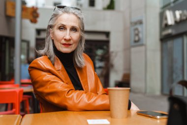 Kahvesini dışarıda içerken kahve içen son sınıf öğrencisi gri beyaz kadın.