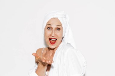 Üst düzey kadın havluyla bağırıyor ve kopyalama alanını beyaz duvarın üzerinde izole ediyor.