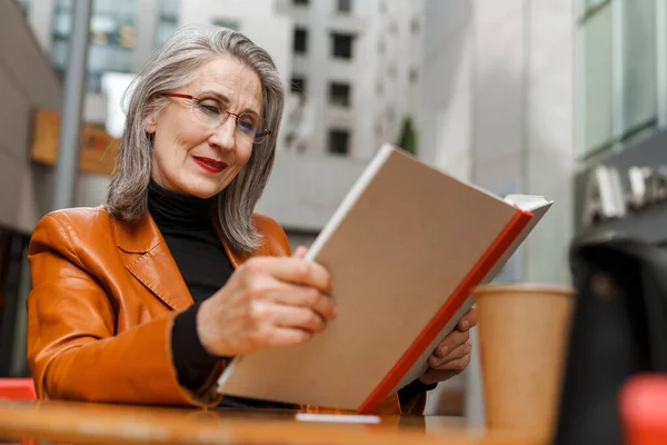 Γκρι Λευκό Ηλικιωμένη Γυναίκα Διαβάζει Βιβλίο Ενώ Κάθεται Καφέ Έξω — Φωτογραφία Αρχείου