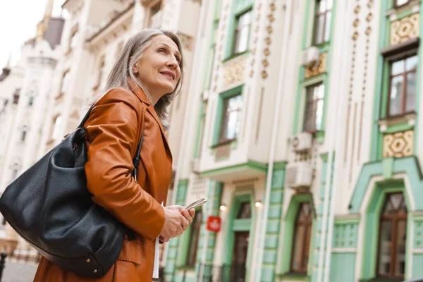 Grijze Senior Vrouw Met Behulp Van Mobiele Telefoon Tijdens Het — Stockfoto